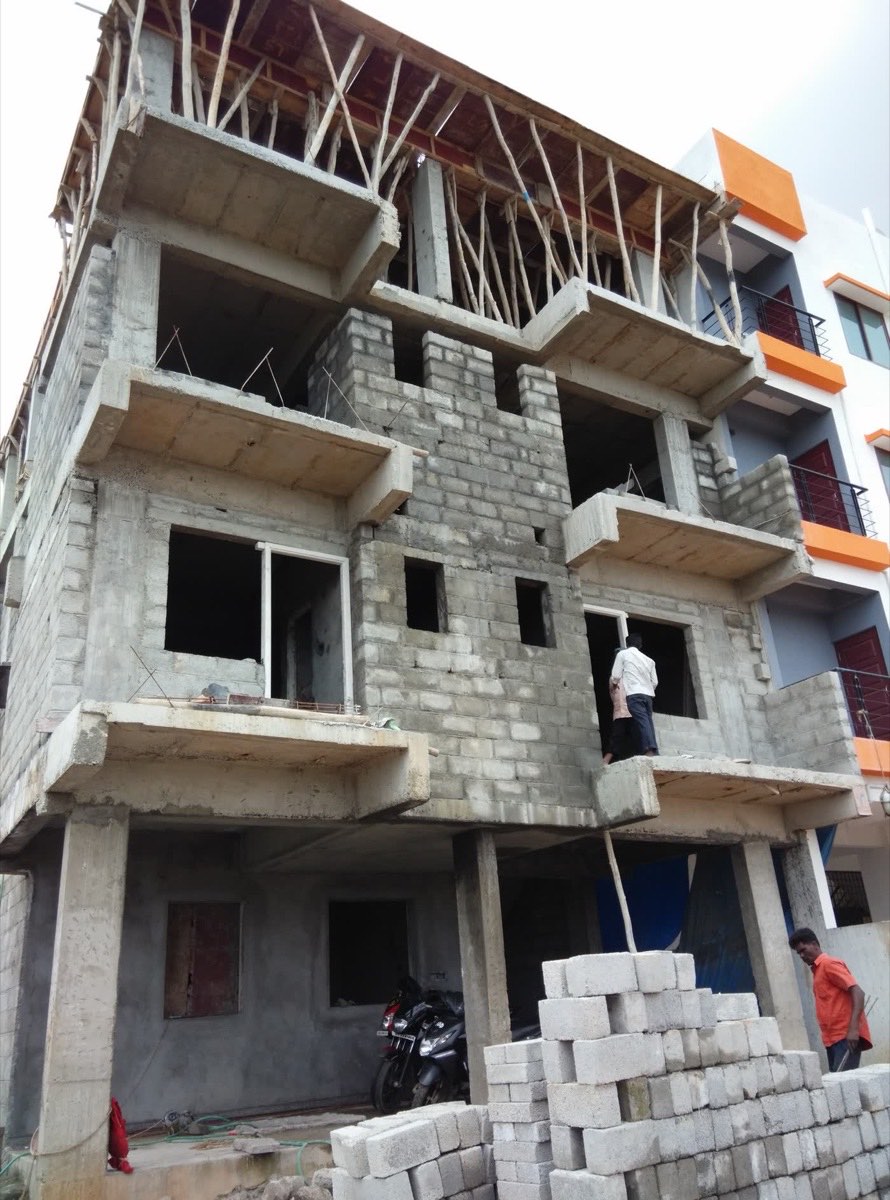 Workers and stacked concrete blocks on a residential construction site in Bangalore during slab and masonry work